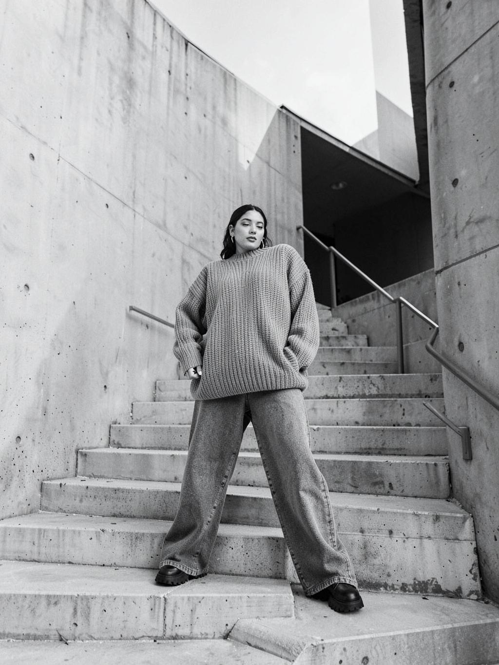 Mujer con jersey oversize en unas escaleras de hormigón